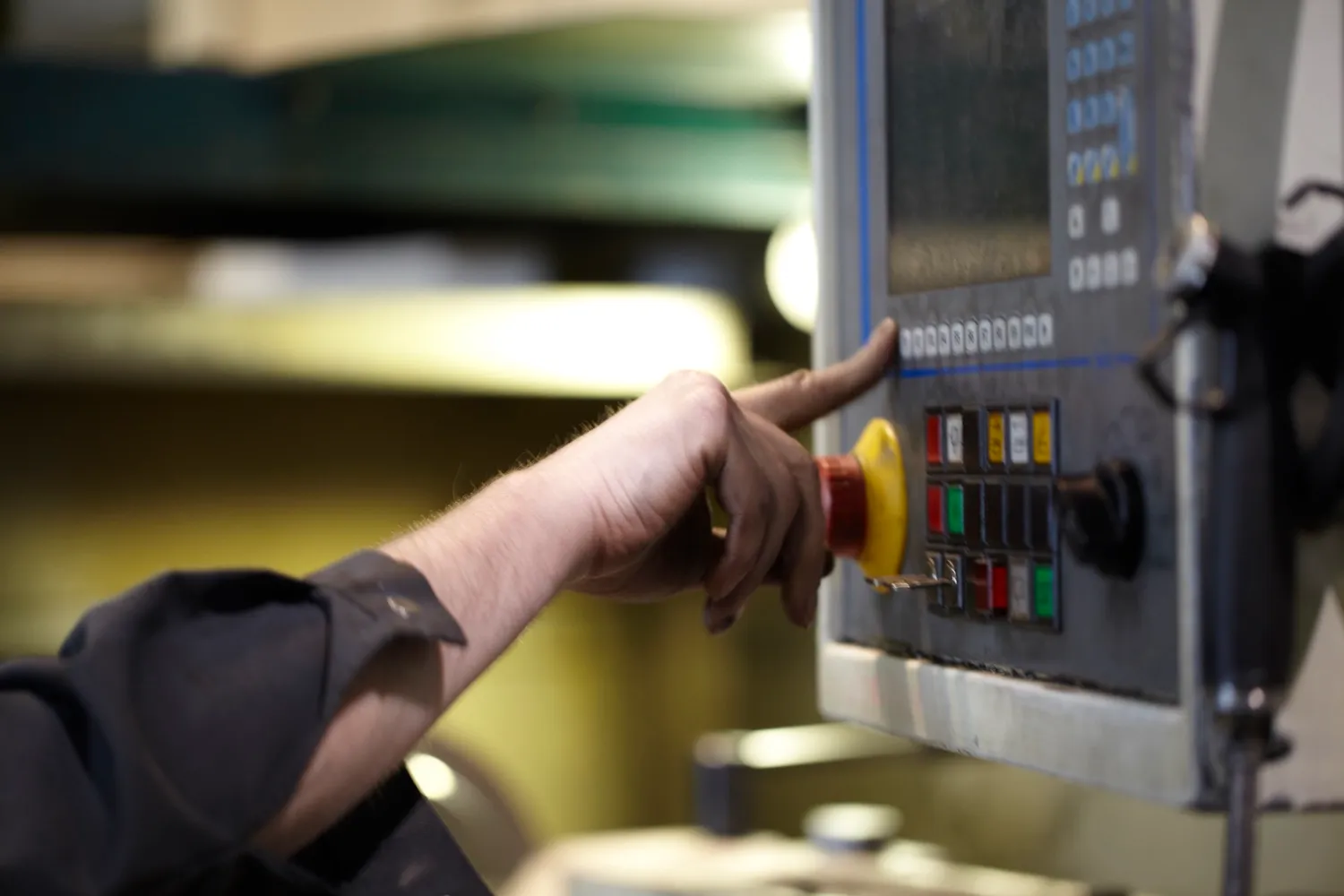 Hand an der Steuerung einer CNC-Maschine